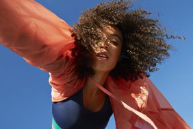 female athlete with curly hair against clear sky
